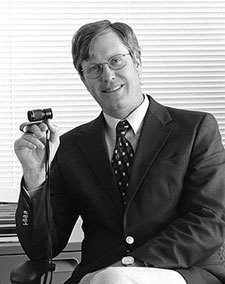 Portrait of John Brabyn holding a lens
