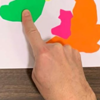 Close-up photo of a person pointing right index finger to Ireland on a map of the British Isles with their other fingers closed.