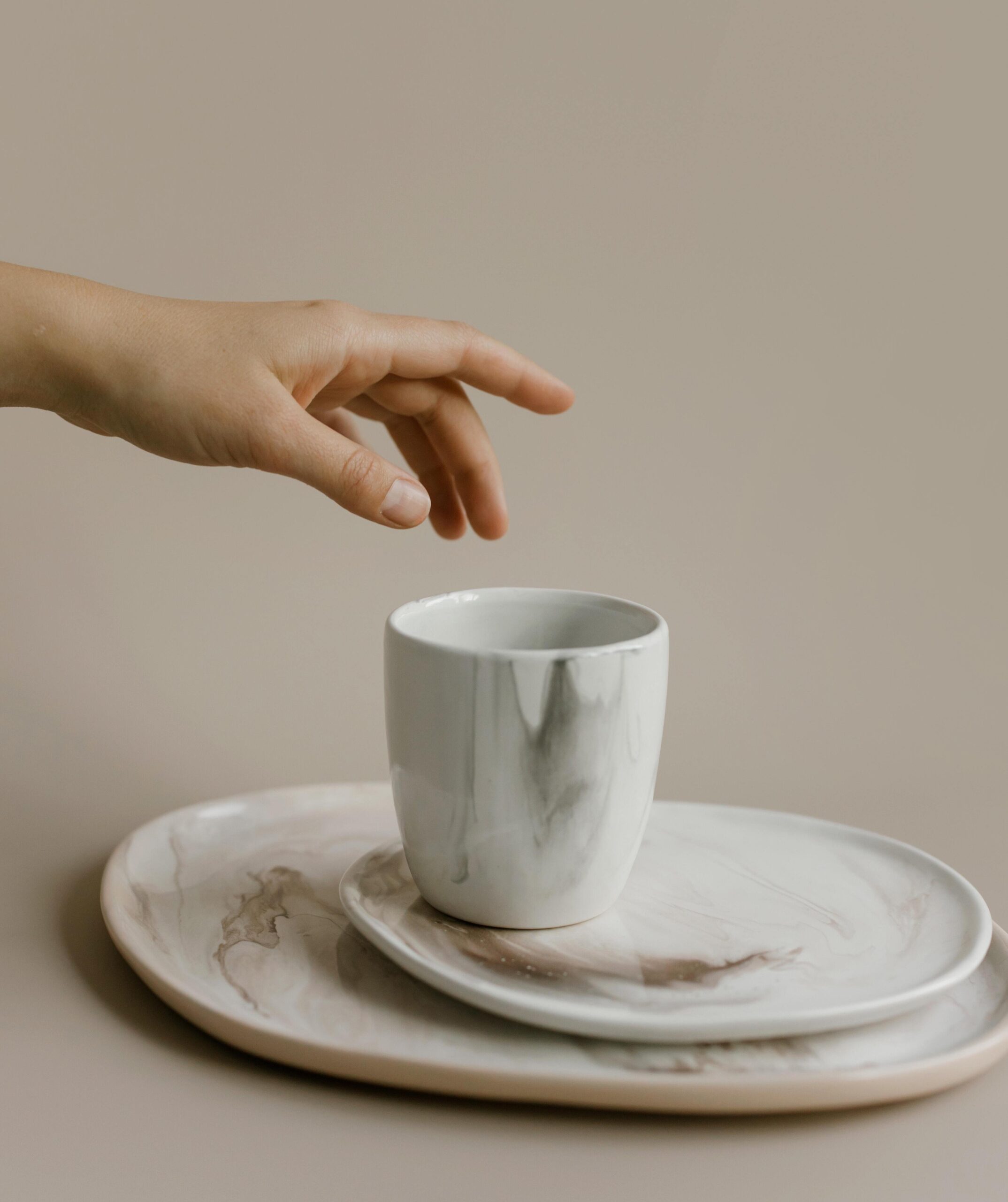 photograph of a person's hand reaching for a cup with a grasp movement that appears to be poorly suited for the task