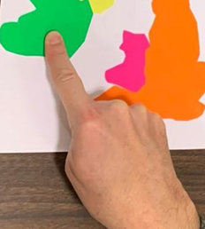 Close-up photo showing person pointing right index finger to Ireland on a map of the British Isles with other fingers closed.
